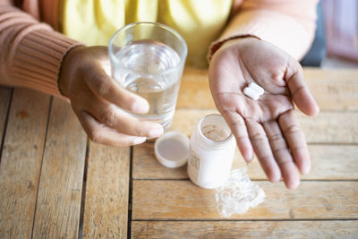 Midsection of woman holding coffee on table