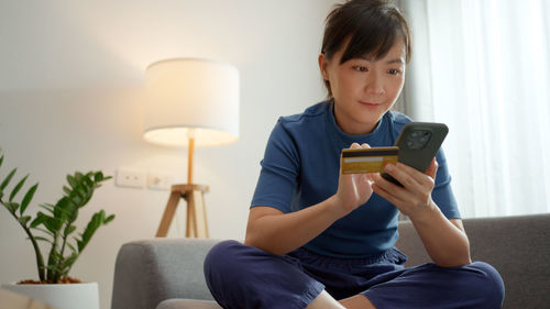 Young woman using phone while sitting at home