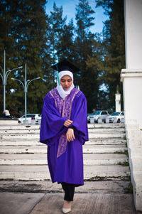 Portrait of smiling woman standing against trees