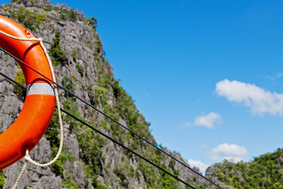 Low angle view of orange hanging on rock against sky