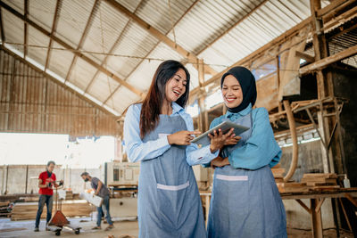 Portrait of smiling young woman standing against building