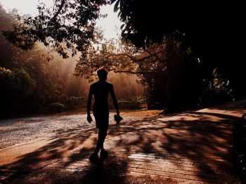 Full length of silhouette shirtless man walking on footpath in forest