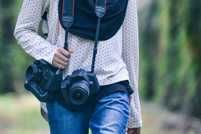 Midsection of woman walking with dslr cameras