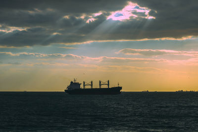 Silhouette boat in sea against sky during sunset