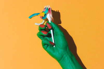 Close-up of human hand against colored background