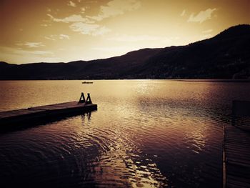 Silhouette man in lake against sky during sunset