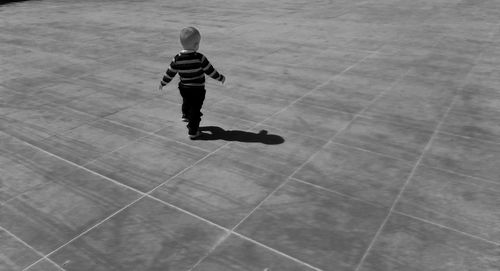 Rear view of boy on walkway during sunny day