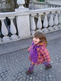 High angle view of cheerful girl in warm clothing walking on footpath