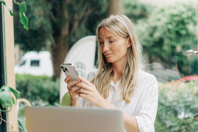 A woman working remotely writes a message on her mobile phone.