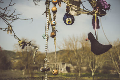 Close-up of decoration hanging on metal chain against sky