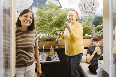 Portrait of smiling woman with mother-in-law and son in balcony