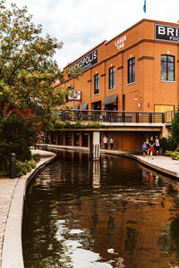 Canal amidst buildings against sky in city