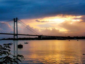 Bridge over river against cloudy sky