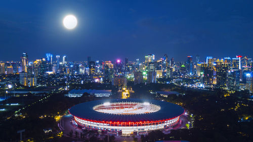 Illuminated carousel in city against sky at night