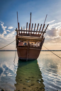 Sailboat moored on sea against sky during sunset