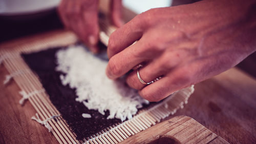 Cropped hands making sushi