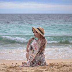 Side view of woman sitting at beach