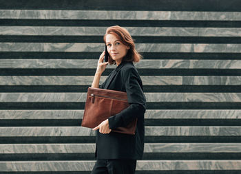 Young woman standing against wall