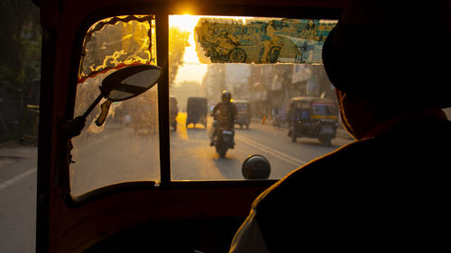 Man driving rickshaw in city during sunset