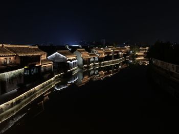 Illuminated buildings in city against clear sky at night