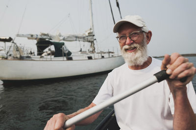 Portrait of senior man rowing boat on sea against sky