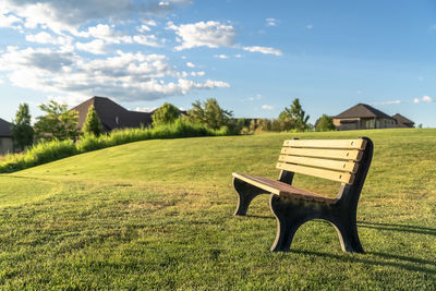 Empty bench on field against sky