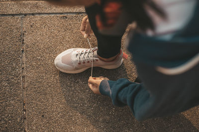 Low section of woman tying shoelace on street