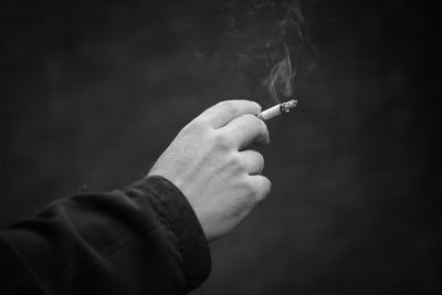 Midsection of man holding cigarette