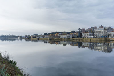 Buildings by river against sky in city