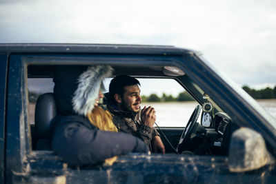 Portrait of smiling woman sitting on car