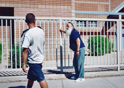 Rear view of men walking on street against building