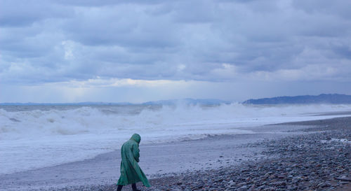 Man walking on beach against sky