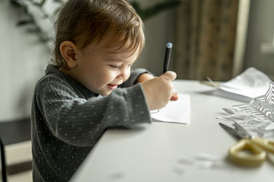 Boy drawing on paper with pencil at table in home