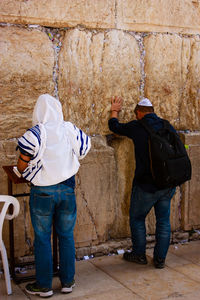 Rear view of men standing against wailing wall