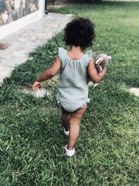 Rear view of girl walking on grassy land