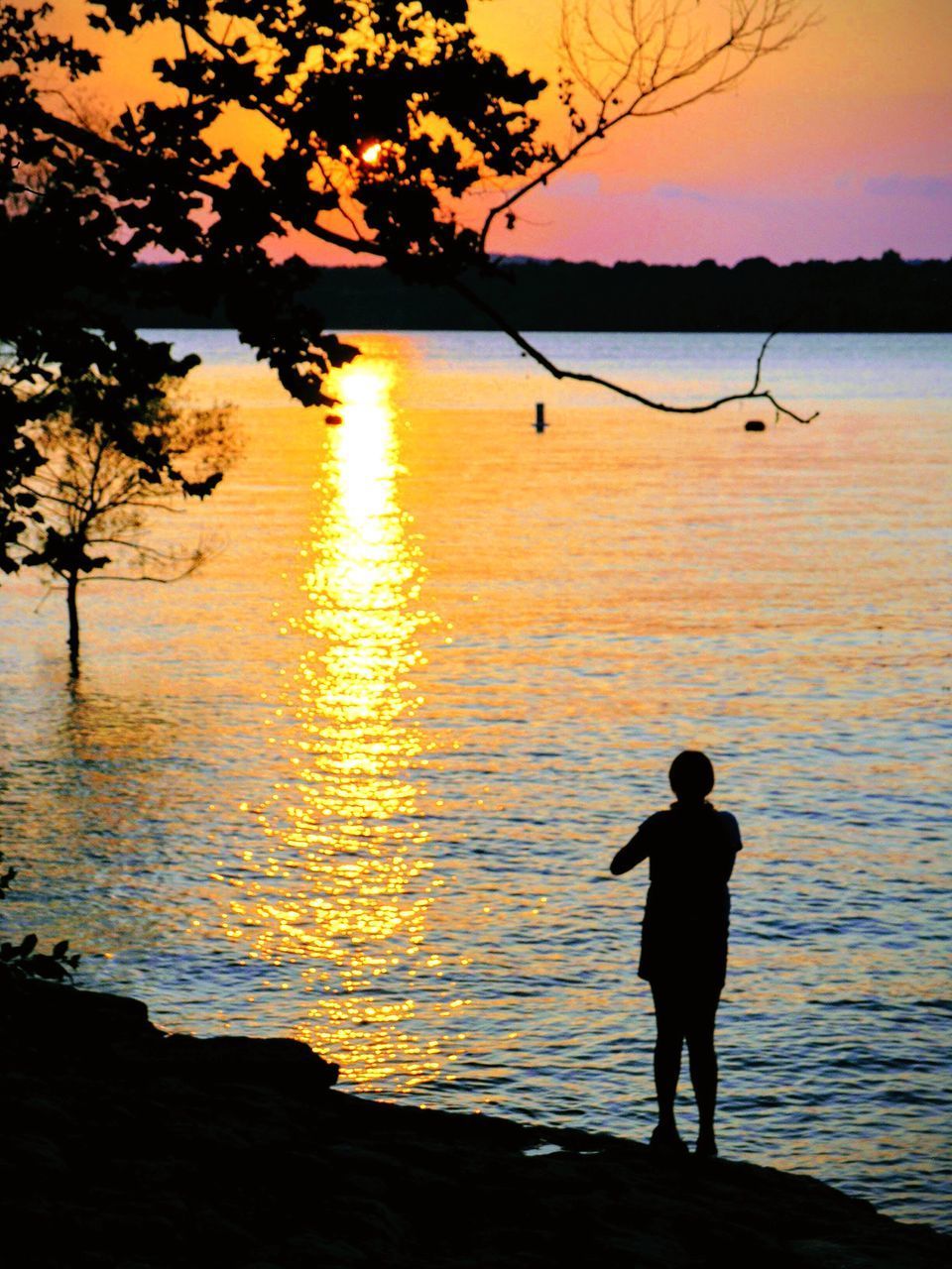 SILHOUETTE MAN STANDING ON BEACH AGAINST ORANGE SKY