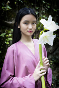 Asian teenage girl in purple blouse holding white flowers in her hands iv