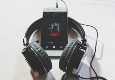 Close-up of mobile phone with headphones on white table