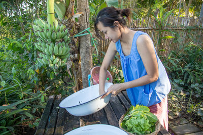 Woman preparing food on table while standing against plants