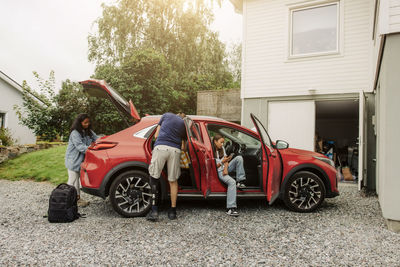 Family loading stuff in electric car near house