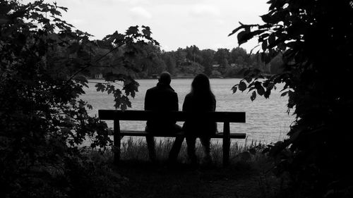 People sitting on bench by lake