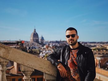 Portrait of young man standing against cityscape