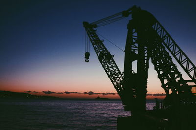 Silhouette of bridge over river against sky