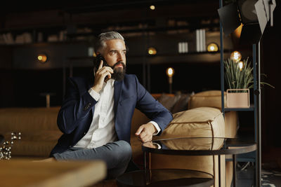 Businessman talking via cell phone in cafe