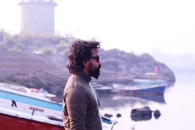 Young man looking at sea against sky