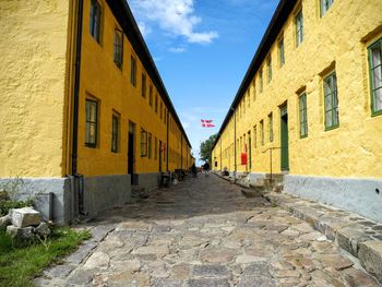 Walkway amidst buildings against sky