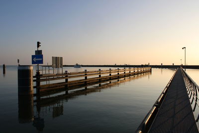 Pier over sea against clear sky during sunset