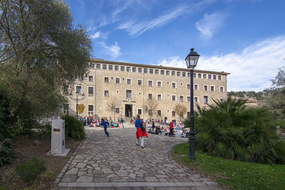 People on street amidst buildings in city against sky