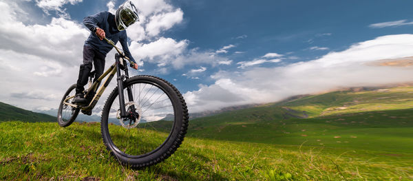 Low section of man riding bicycle on field