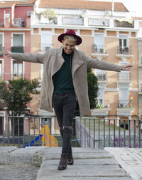 Fashion young model with grey jacket and red hat balancing in city
